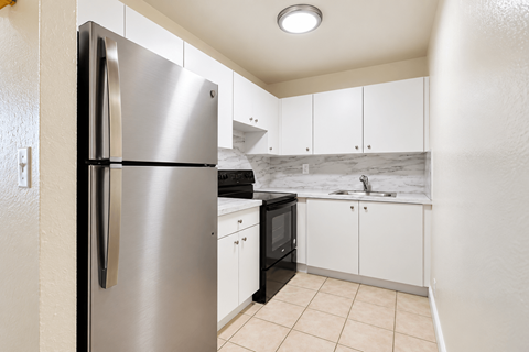 A kitchen with a stainless steel refrigerator and white cabinets.