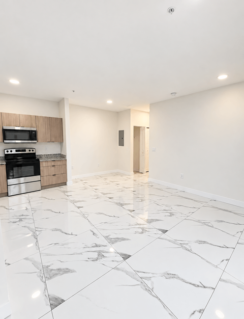 A kitchen with a marble floor and a microwave above the stove.