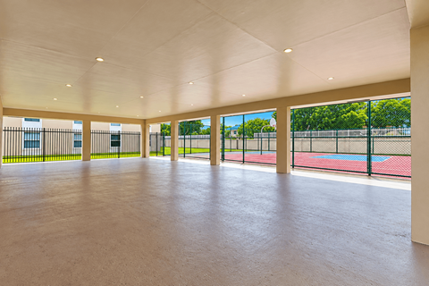 A spacious indoor area with a tennis court visible through the windows.