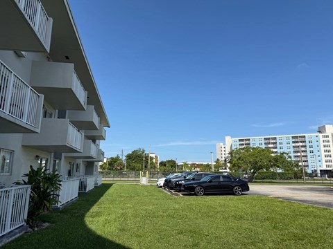 A black car is parked in a parking lot in front of a white building.