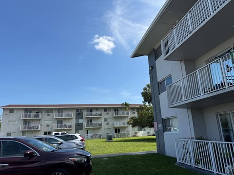 A row of cars parked in front of apartment buildings.