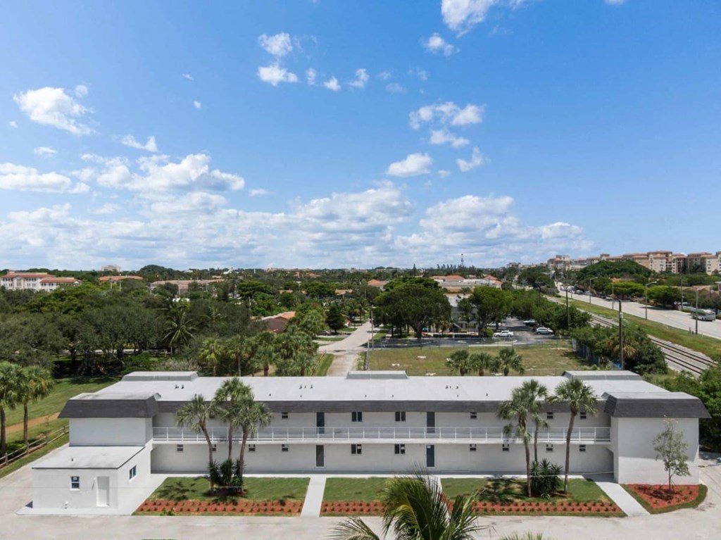 an aerial view of a white building with palm trees