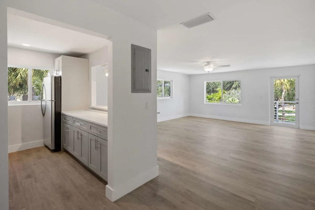 an empty living room and kitchen with a refrigerator