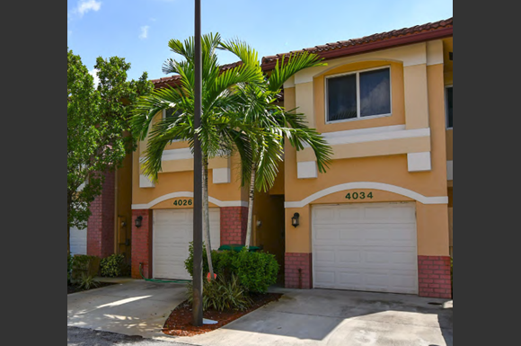 a house with two garage doors and a palm tree in front of it