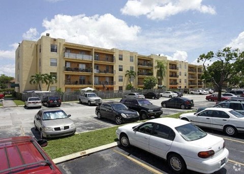 a parking lot filled with cars in front of an apartment building