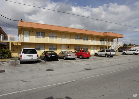 the parking lot is full of cars in front of a yellow building