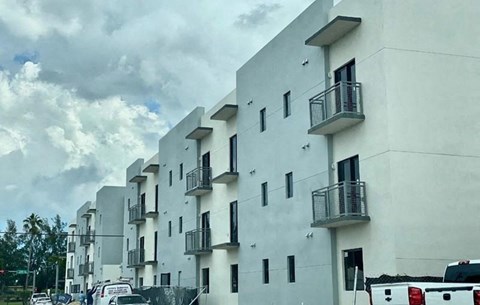 a white building with balconies and cars parked in front of it