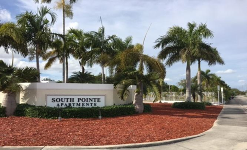 a sign for south point apartments in front of palm trees