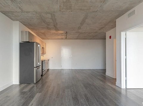 an empty living room with a stainless steel refrigerator