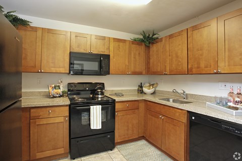 A kitchen with wooden cabinets and black appliances.