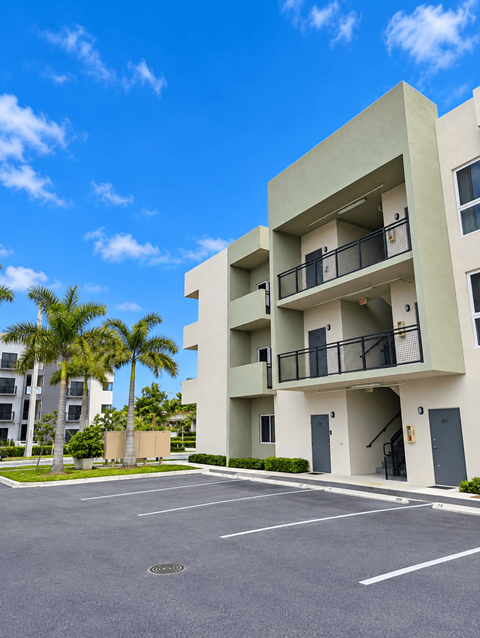 A modern apartment building with a parking lot in front.