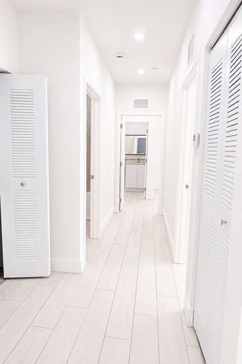 A white kitchen with a refrigerator on the left and a white cabinet on the right.