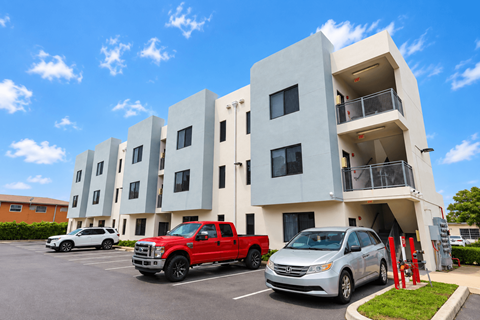 A red truck is parked in front of a white building.