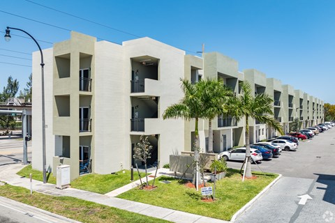 A row of modern apartment buildings with cars parked in front.