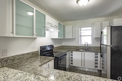 A kitchen with granite countertops and white cabinets.