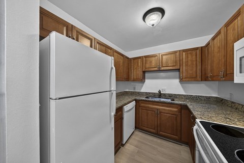 A kitchen with a white refrigerator and wooden cabinets.