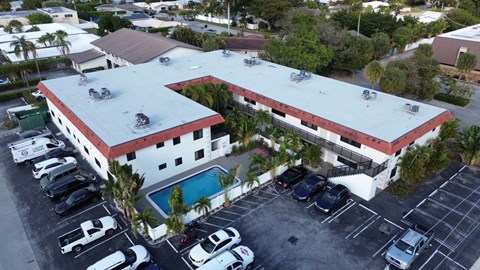 A large white building with a red roof and a pool in the courtyard.