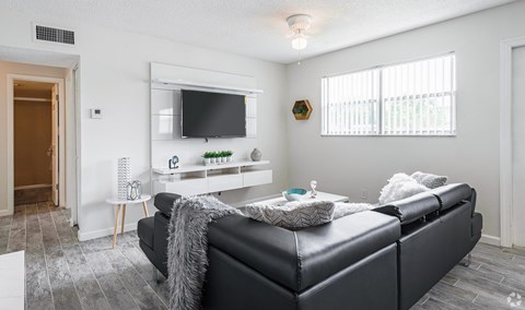 A black leather sofa with a grey throw blanket on it in a living room.