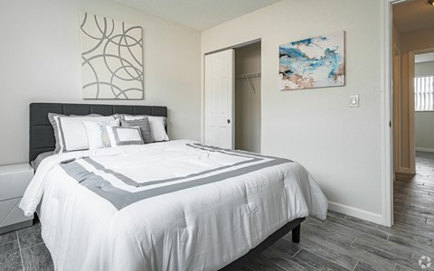 A bedroom with a large bed and a painting on the wall.