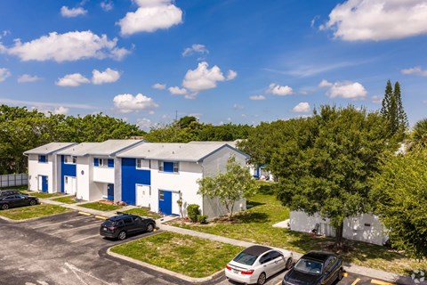 A parking lot with cars and a building with blue doors.