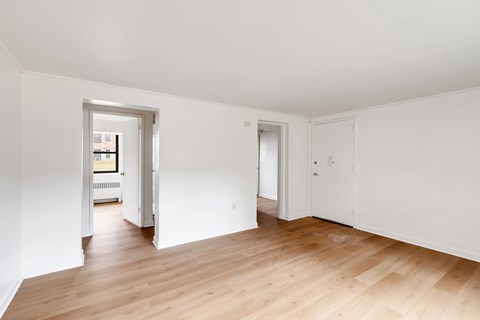 A room with white walls and wooden flooring with two doors.