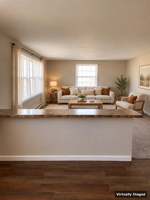 A living room with a couch, chair, and a table with a vase of flowers on it.