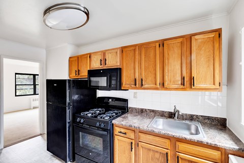 A kitchen with wooden cabinets and black appliances.