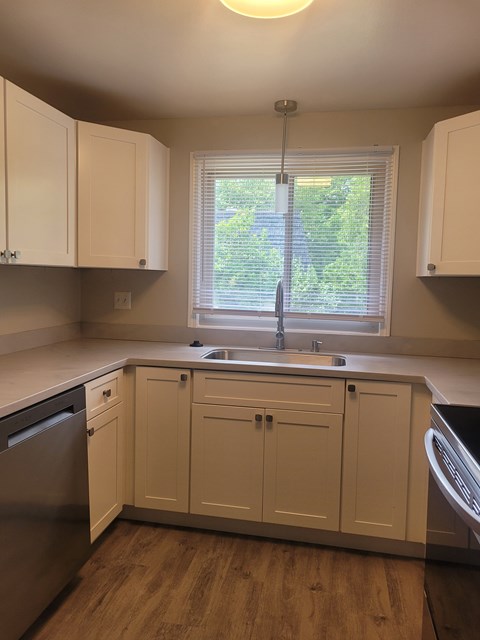 A kitchen with white cabinets and a window.