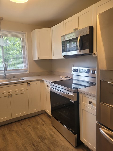 A kitchen with white cabinets and a black microwave above the stove.