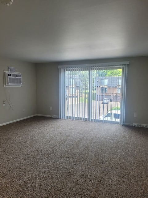 A room with a carpet floor and a window with blinds.