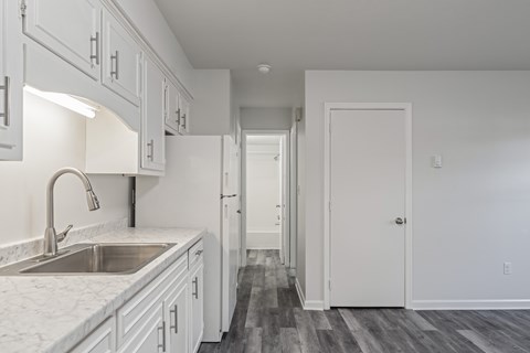 A kitchen with white cabinets and a marble countertop.