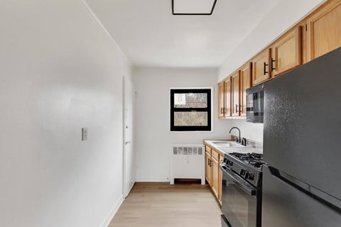 A kitchen with a black fridge and wooden cabinets.
