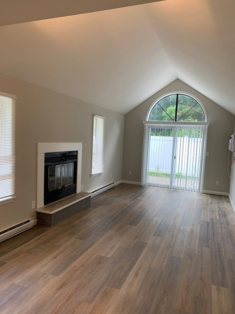 A room with a fireplace and wood flooring.