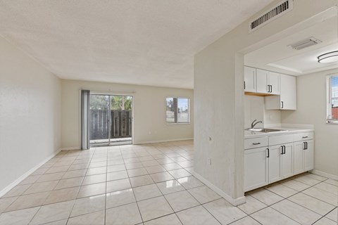A spacious, empty room with white cabinets and a tiled floor.