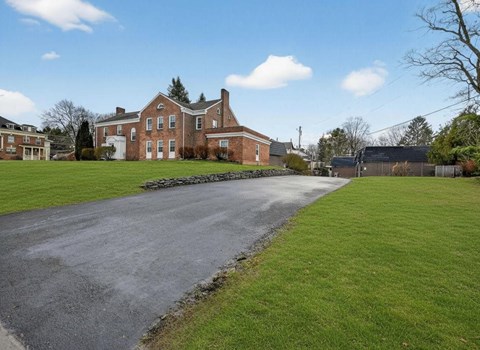 A large brick house with a long driveway in front.