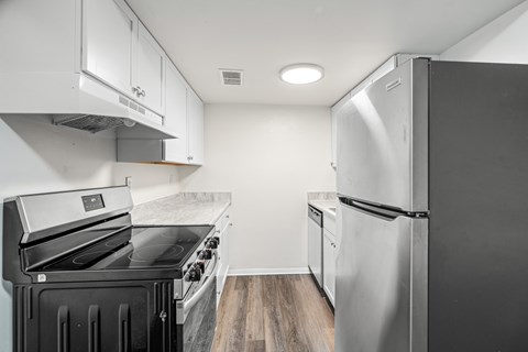 A kitchen with a black stove top oven and a silver refrigerator.