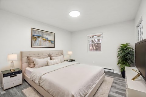 A bedroom with a large bed and a painting on the wall.