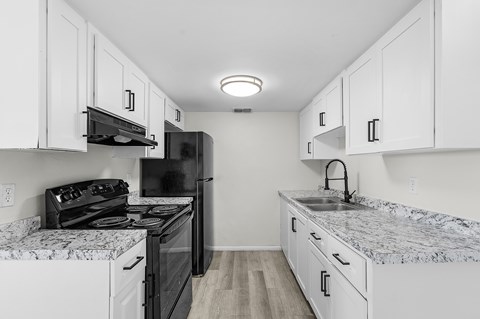 A kitchen with black appliances and white cabinets.