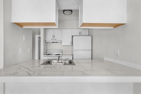 A kitchen with white cabinets and a marble countertop.