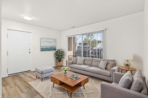 A living room with a grey couch, a coffee table, and a painting on the wall.