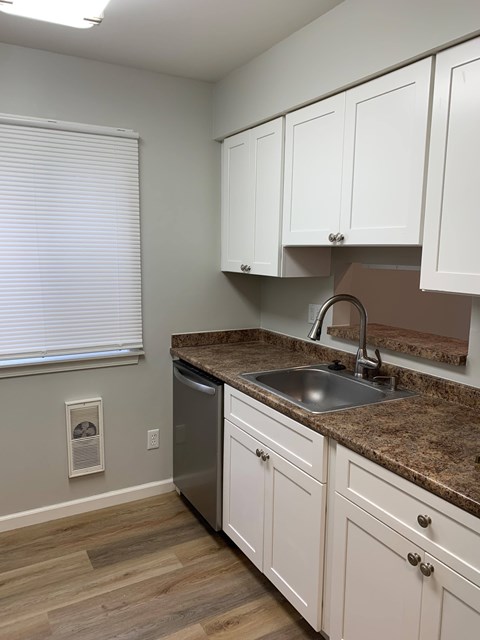 A kitchen with white cabinets and a granite countertop.