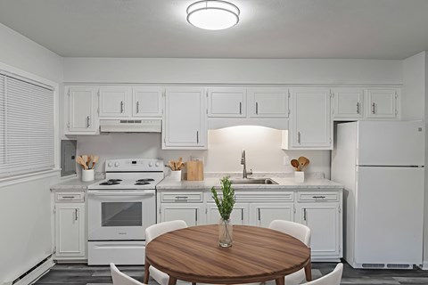 A white kitchen with a wooden table and chairs.