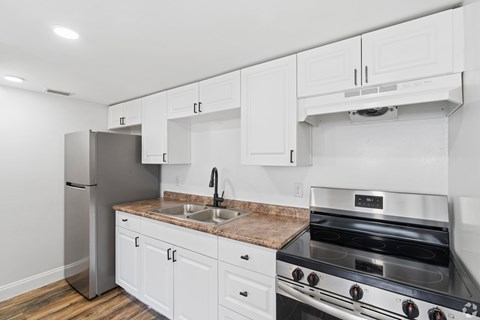 A kitchen with white cabinets and a stainless steel refrigerator.