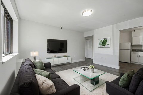 A modern living room with a black couch and a glass coffee table.