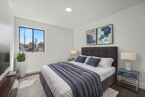 A bedroom with a large bed and a window overlooking a residential area.
