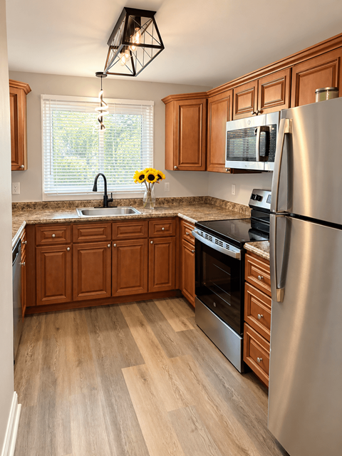 A kitchen with wooden cabinets and a stainless steel refrigerator.