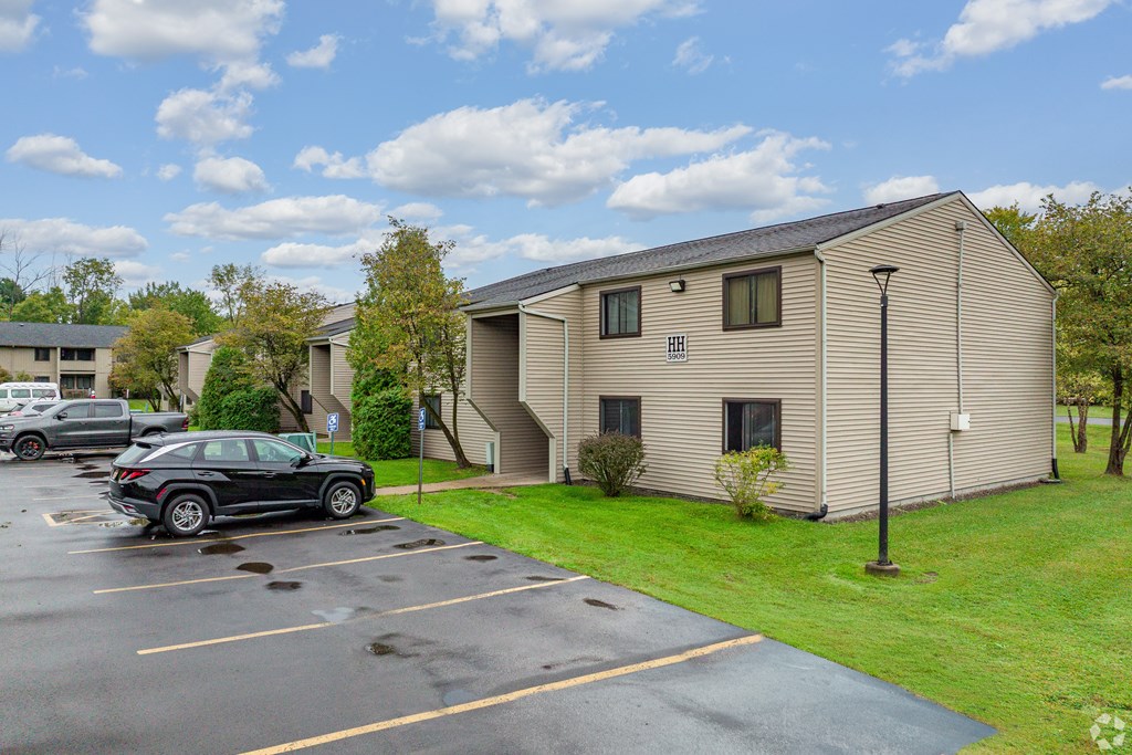 A black car is parked in a parking lot in front of a building.
