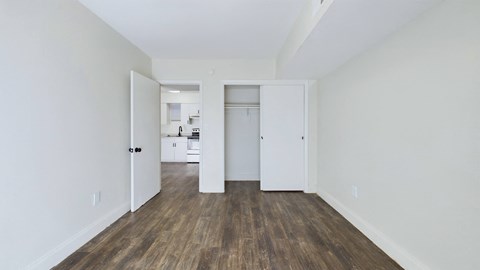 A room with white walls and wood flooring with two open doors.