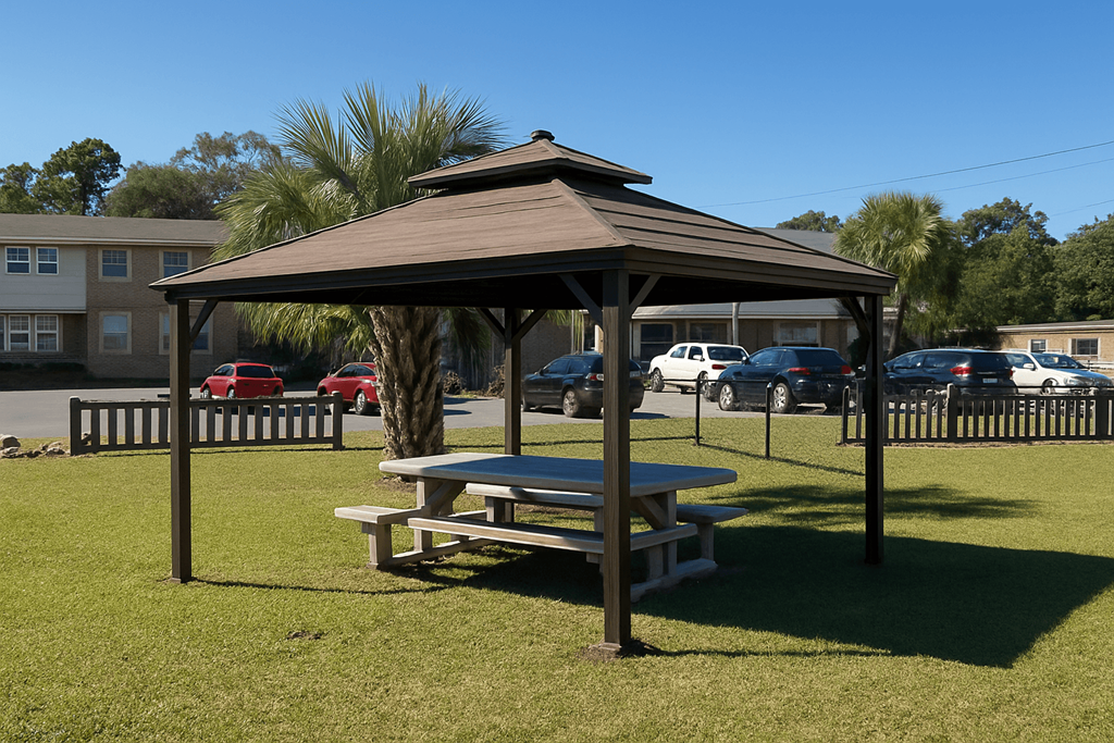 A pavilion with a picnic table in front of a parking lot.