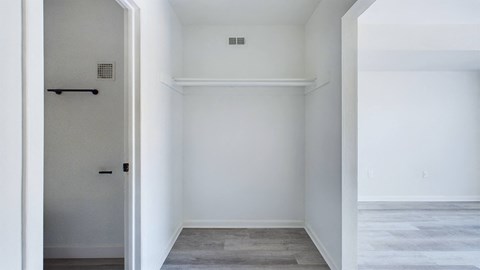 A white room with a door and a small vent on the wall.